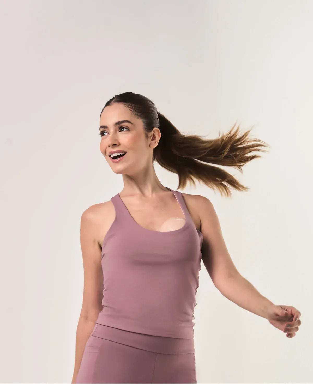 A mother holding her baby, wearing the Momdrops heated wearable breast pump under a knit sweater